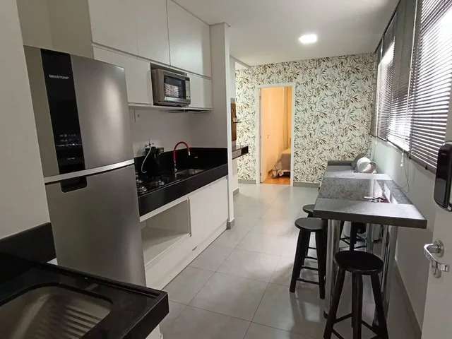 Varanda com mesa, cadeiras, plantas e cordão de luzes ao entardecer