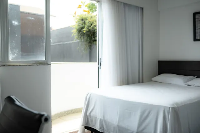 Predio de apartamentos moderno com fachada de vidro refletindo o ceu azul em area urbana