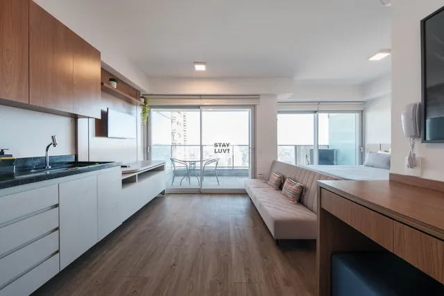 Sala de estar moderna com sofá claro, plantas e janela ampla