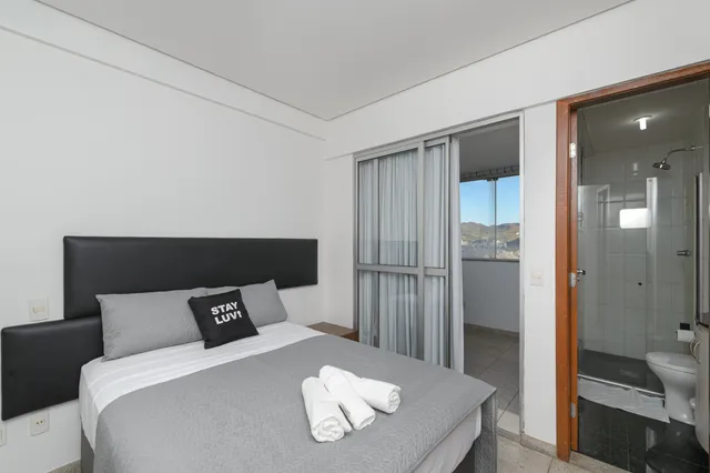Sofá cinza de dois lugares em sala de apartamento compacto com iluminação natural