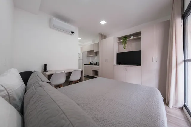 Sala de apartamento iluminada com janelas abertas e plantas decorativas sobre bancada
