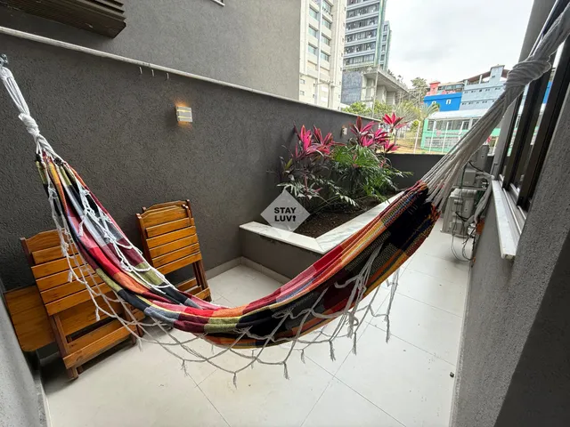Sala de apartamento decorada com tapete de pelo baixo e sofá claro em ambiente bem iluminado