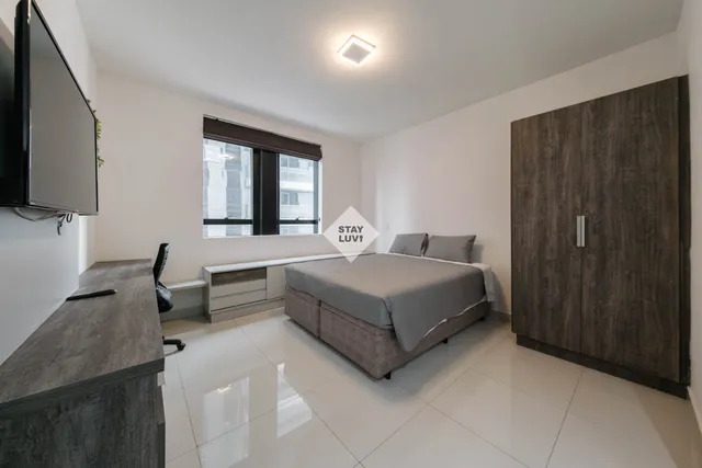 Cozinha equipada de apartamento de temporada com geladeira, fogão e micro-ondas em bom estado