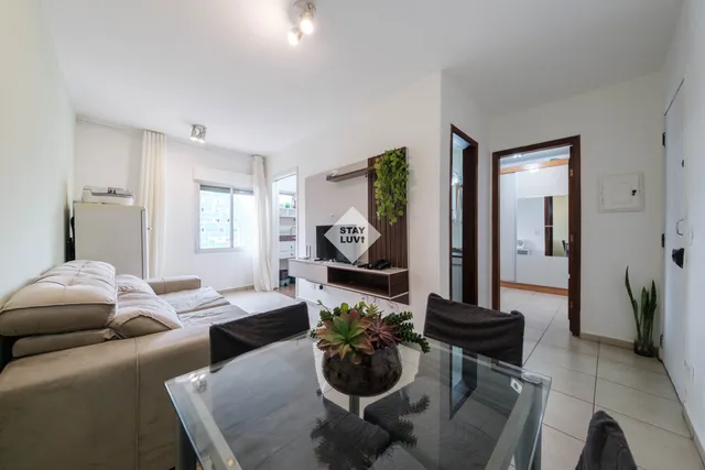 Sala de apartamento compartilhado com sofá, mesa de estudos e boa iluminação natural