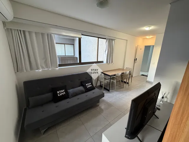 Sala de estar de apartamento mobiliado com sofá, mesa de centro e televisão