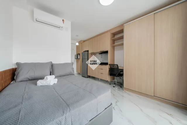 Terreno vazio em área urbana com prédios ao fundo e placa de obra em construção